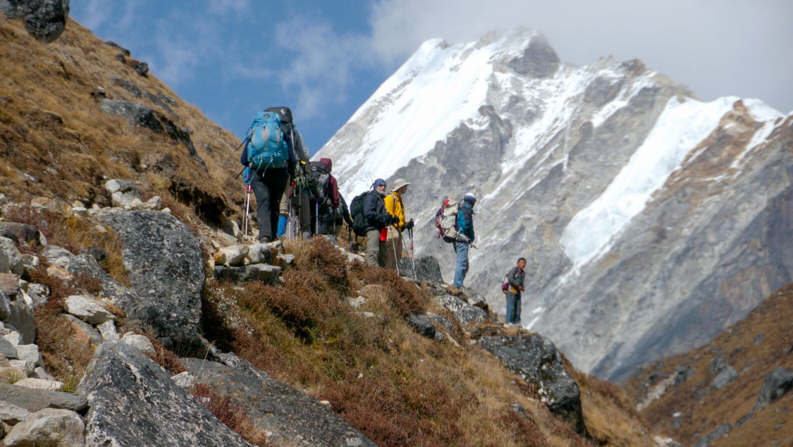 Groupe de trekkeurs progressant sur un sentier rocailleux en haute altitude.