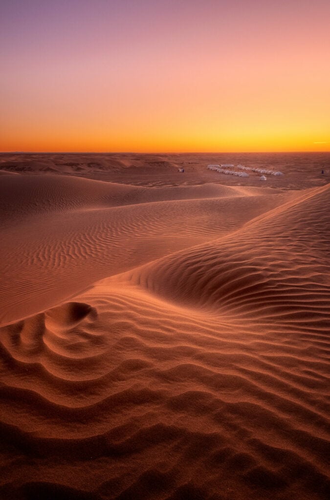 Dunes orangées sculptées par la lumière du coucher du soleil.