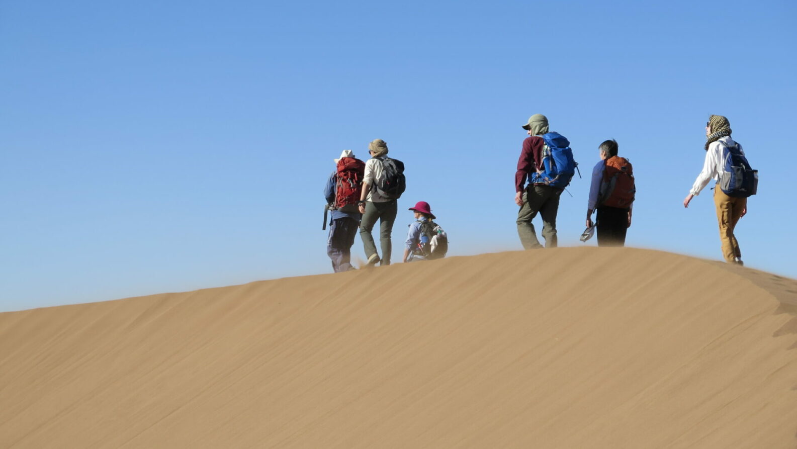 Petite équipe en haut d’une dune, observant le paysage infini.