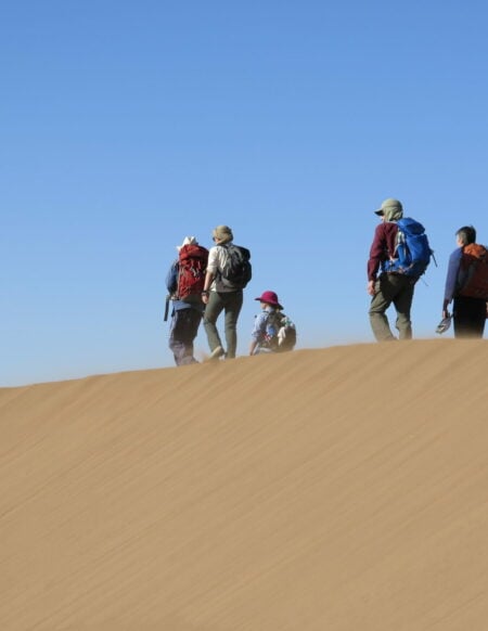 Petite équipe en haut d’une dune, observant le paysage infini.