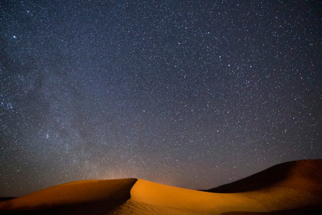 Ciel étoilé au-dessus d’une dune parfaitement dessinée par le vent.