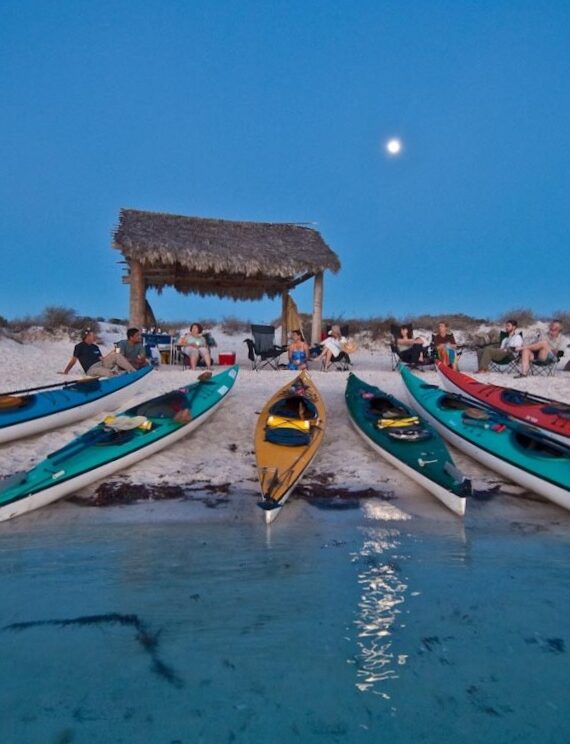 Kayaks de mer alignés sur la plage au crépuscule en Basse-Californie, aventure avec Karavaniers