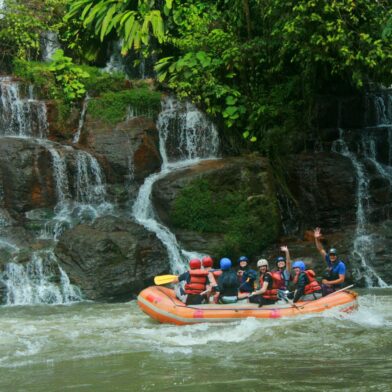 Groupe en rafting sur une rivière entourée de cascades.
