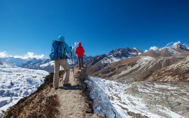 Randonneurs parcourant un sentier entouré de neige et de montagnes