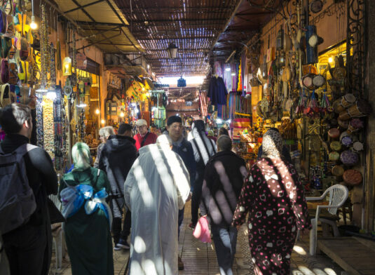 Scène animée dans un souk coloré, entre étoffes et épices marocaines