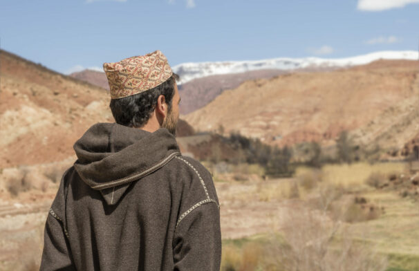 Homme de dos en djellaba contemplant les montagnes, ambiance paisible du Haut Atlas