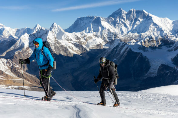 Corde de marcheurs encordés en pleine progression sur glacier, face à l’Himalaya.