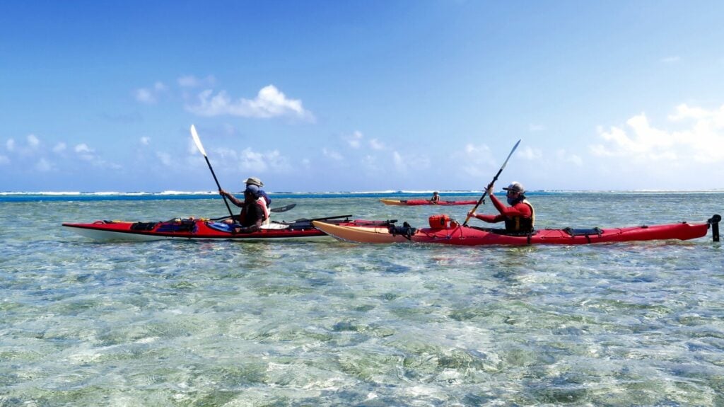 Deux kayakistes glissant sur une mer peu profonde et cristalline.
