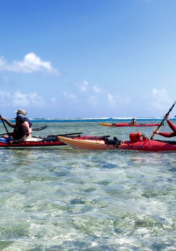 Deux kayakistes glissant sur une mer peu profonde et cristalline.