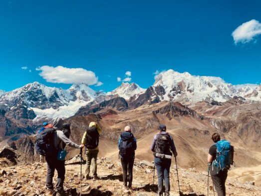 Groupe de randonneurs face aux montagnes du Huayhuash sous un ciel bleu, lors d'un voyage organisé au Pérou.