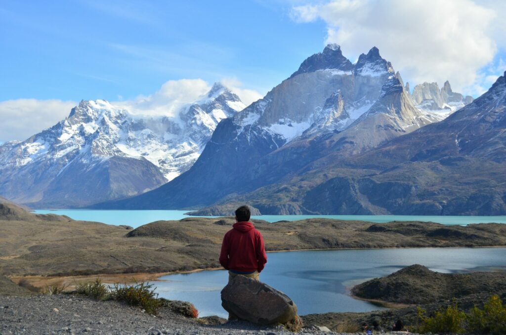 Randonneuse marquant une pause dans son trek, profitant de la vue face aux paysages grandioses de Torres del Paine, en Patagonie.
