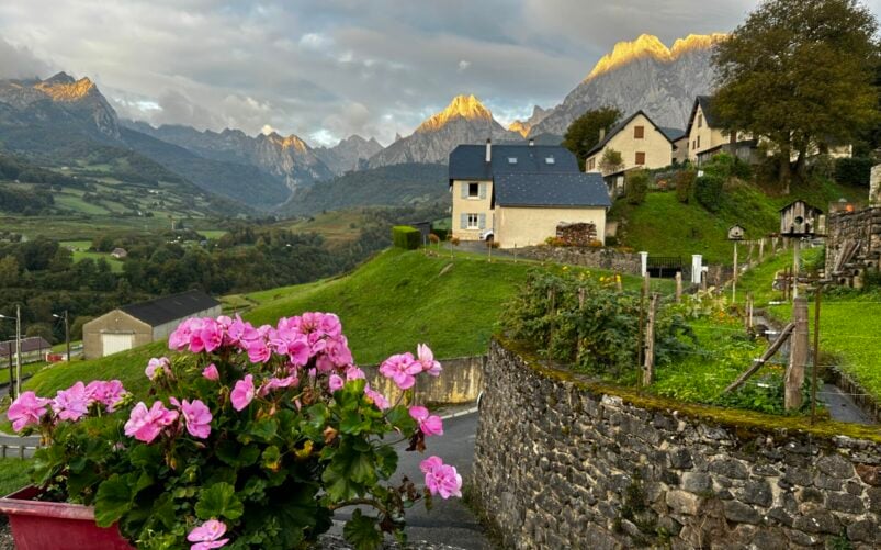 Maison typique basque entourée de fleurs avec les montagnes en toile de fond
