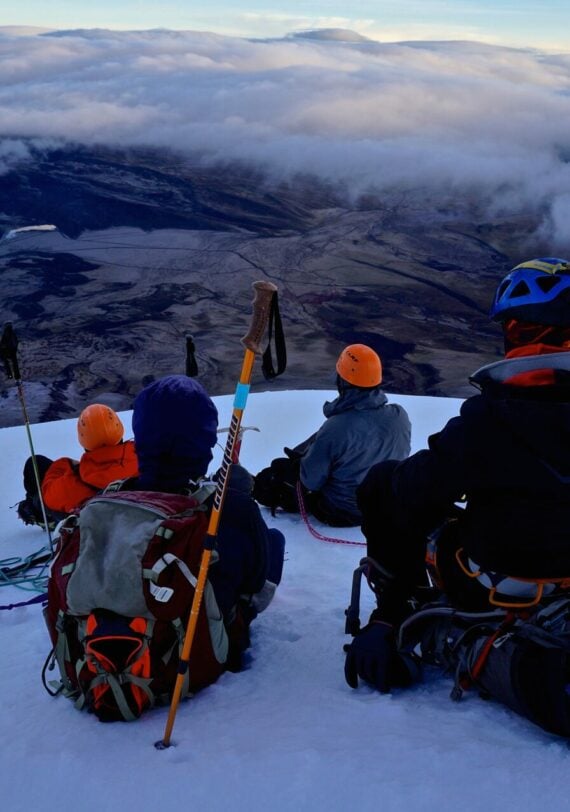 Alpinistes Karavaniers au sommet enneigé du Cotopaxi en Équateur, vue sur les vallées et nuages.
