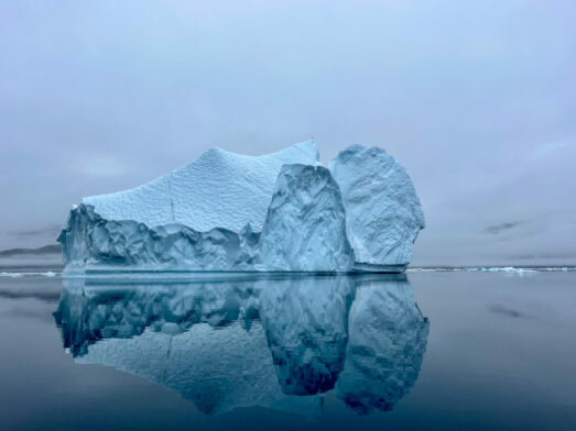 Iceberg monumental aux reflets parfaits dans les eaux calmes d’un fjord arctique