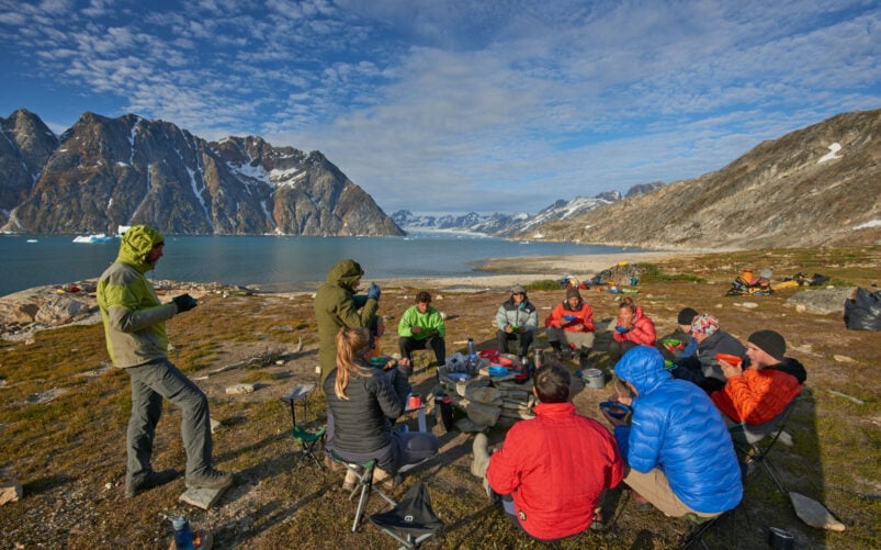 Groupe d’aventuriers assis autour d’un campement près d’un fjord au Groenland.