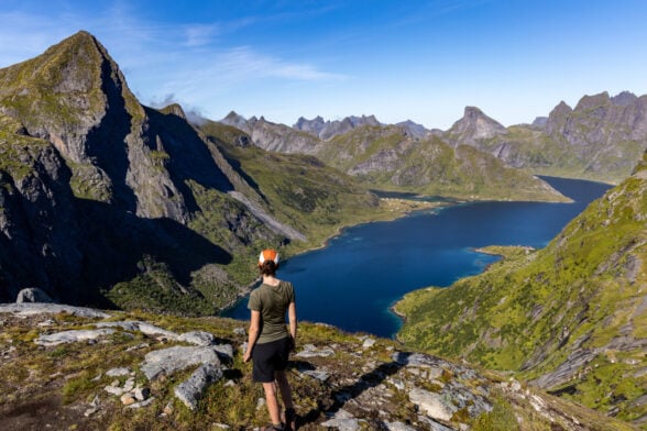 Randonneur face à un lac alpin entouré de pics escarpés dans les îles Lofoten