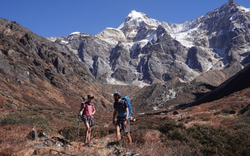 Deux randonneurs sur un sentier de haute montagne avec pics enneigés du Kangchenjunga en arrière-plan, Népal.