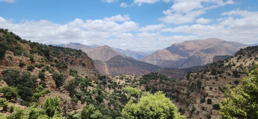 Vue panoramique des montagnes de l’Atlas marocain sous un ciel partiellement nuageux.