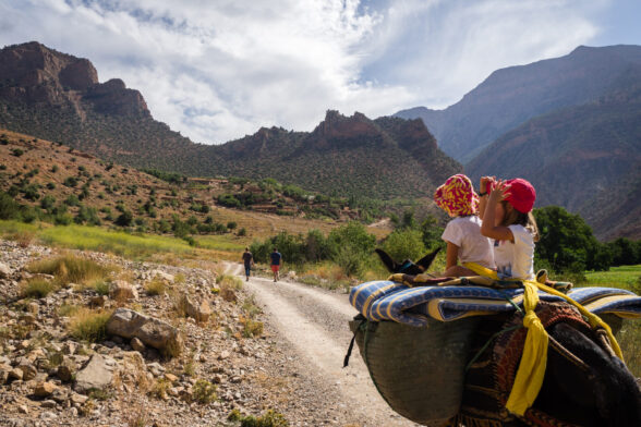 Balade familiale sur un sentier de montagne dans le Haut Atlas, lors d'une randonnée en famille au Maroc, avec des mulets.