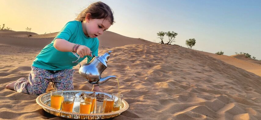 Service du thé marocain dans les dunes, par une jeune fille concentrée.