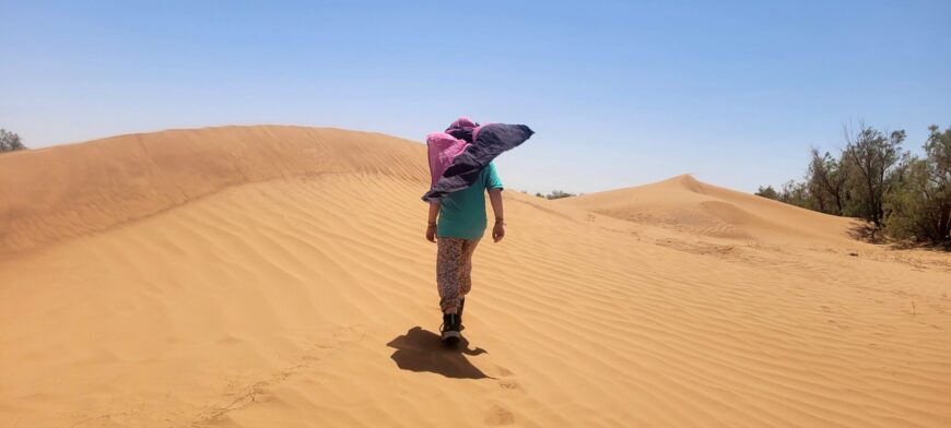 Enfant debout dans le désert, protégé du soleil par un chèche.