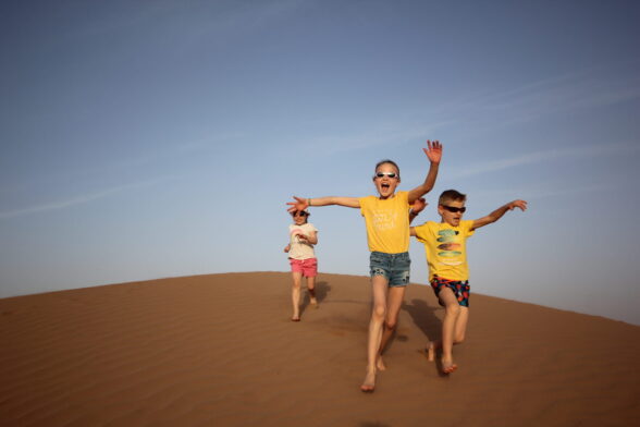 Jeux dans les dunes : enfants courant dans le sable sous le soleil marocain.