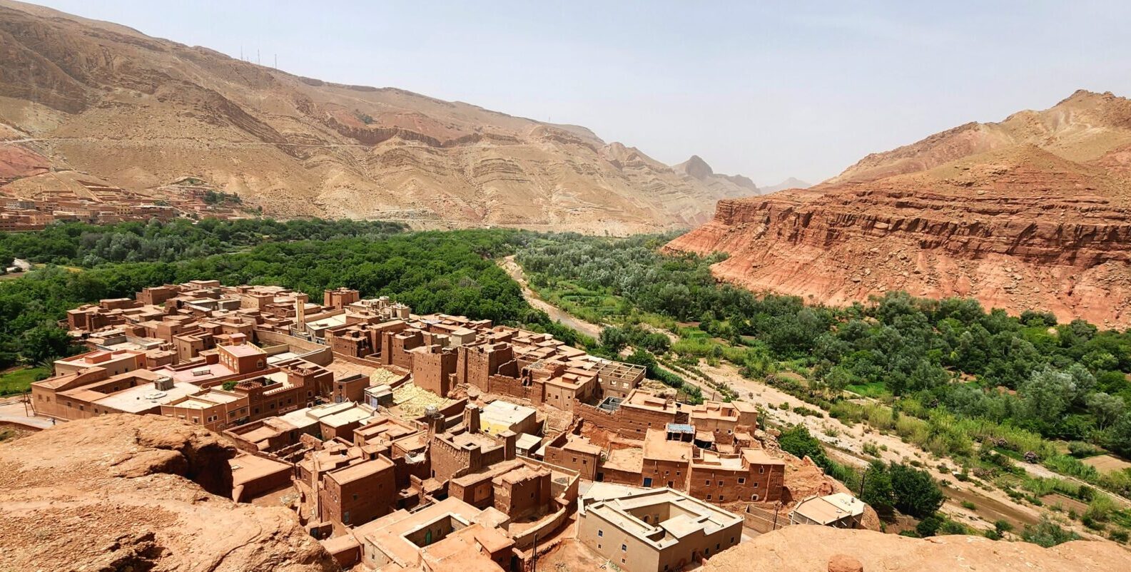 Vue aérienne d’un village en pisé entouré d’une oasis verdoyante dans la vallée des roses