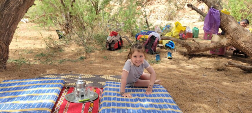 Pause pique-nique dans un sous-bois marocain avec des enfants assis sur une nappe.