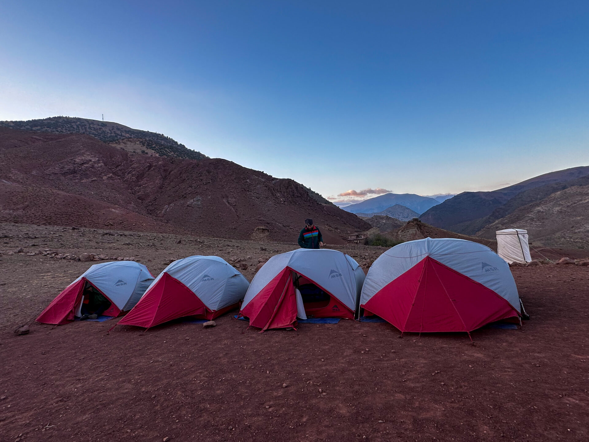 Campement de tentes dans un décor aride du Haut Atlas, sous un ciel dégagé