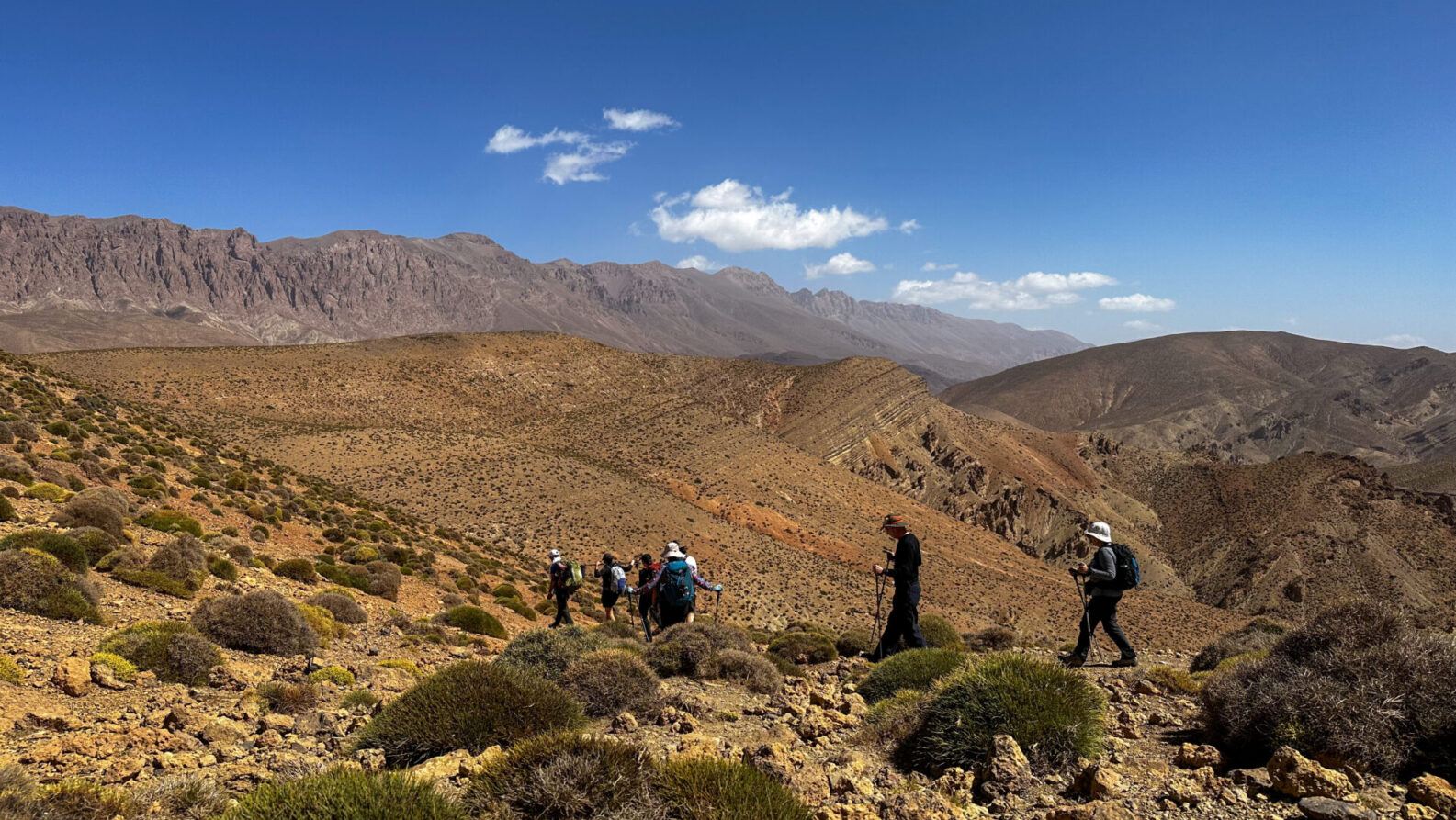 Randonnée à travers les collines arides de l’Anti-Atlas sous un ciel bleu profond.