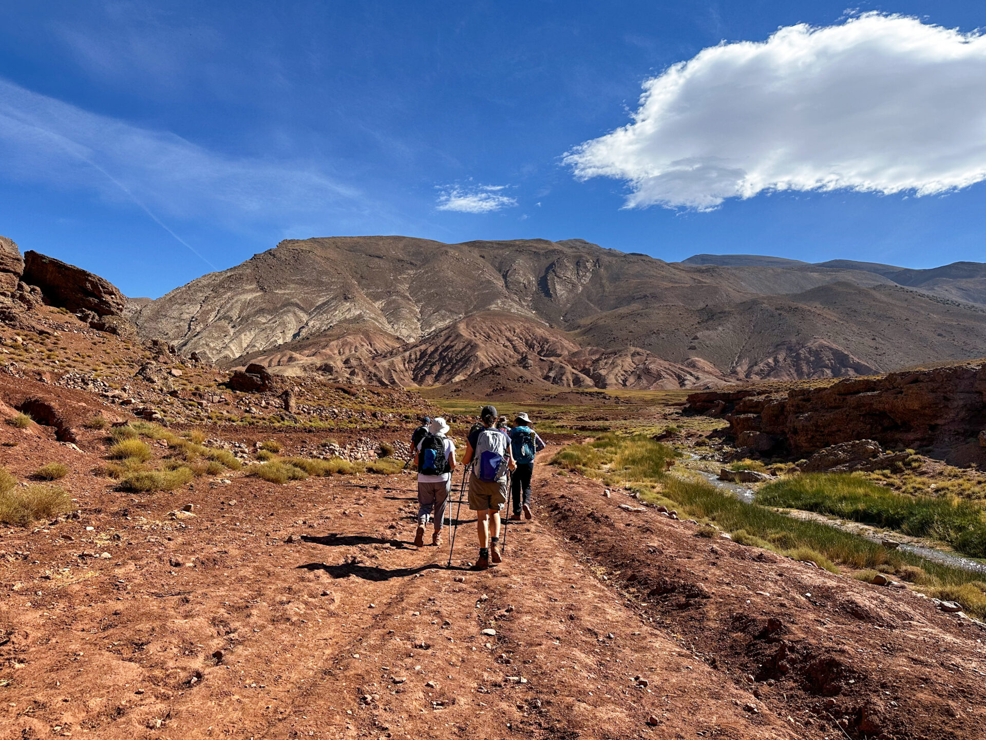 Randonneurs sur un sentier ocre au pied des montagnes marocaines