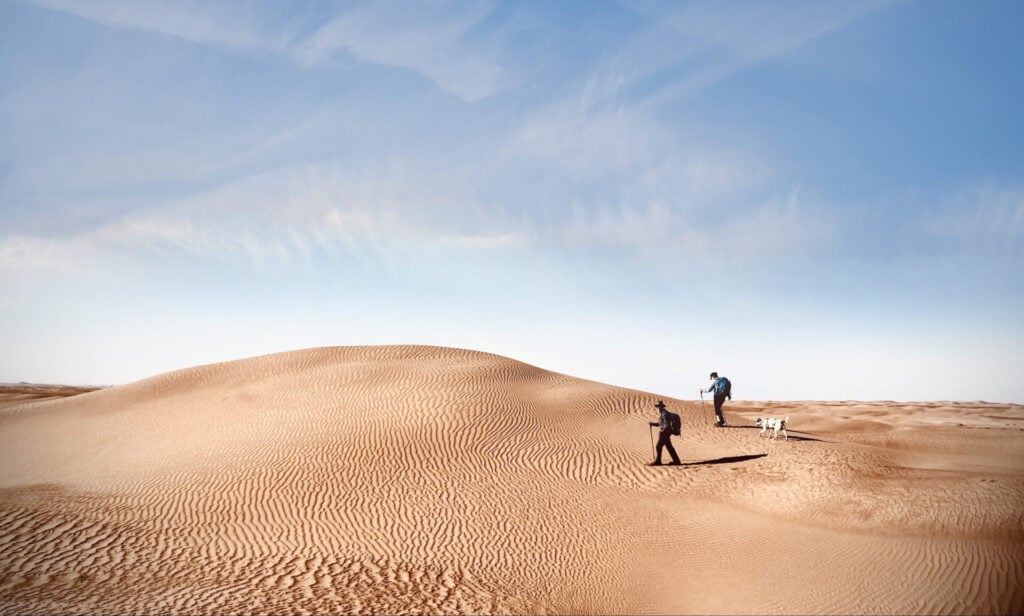 Marcheurs sur les dunes ondulantes du désert marocain, sous un ciel limpide