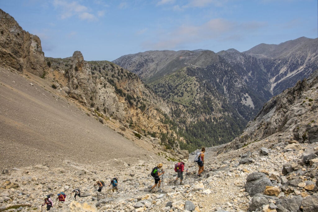 Groupe de randonneurs traversant un sentier rocailleux en montagne.