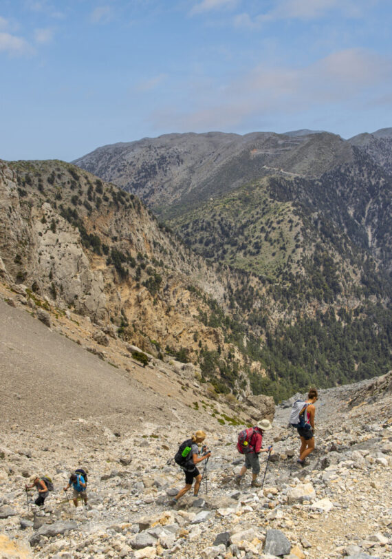 Groupe de randonneurs traversant un sentier rocailleux en montagne.