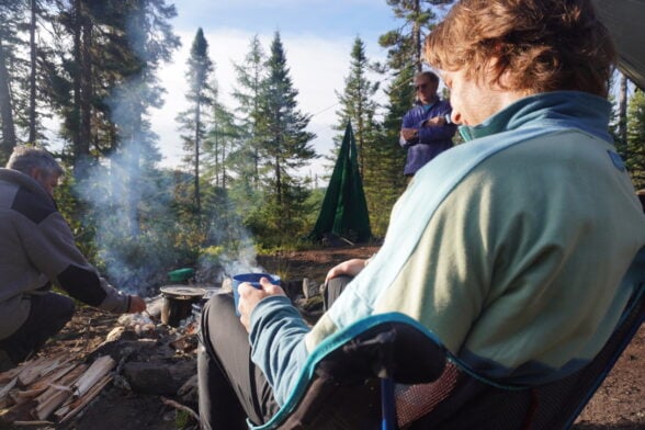 Personne assise avec un appareil photo, face à la rivière.