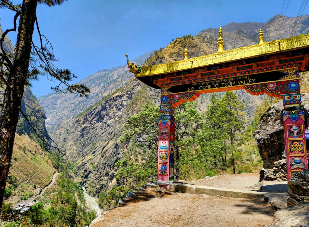 Porte colorée tibétaine marquant l’entrée de la vallée de Tsum au Népal, un passage emblématique pour les voyageurs en trek avec Karavaniers, entre culture et aventure en haute montagne.
