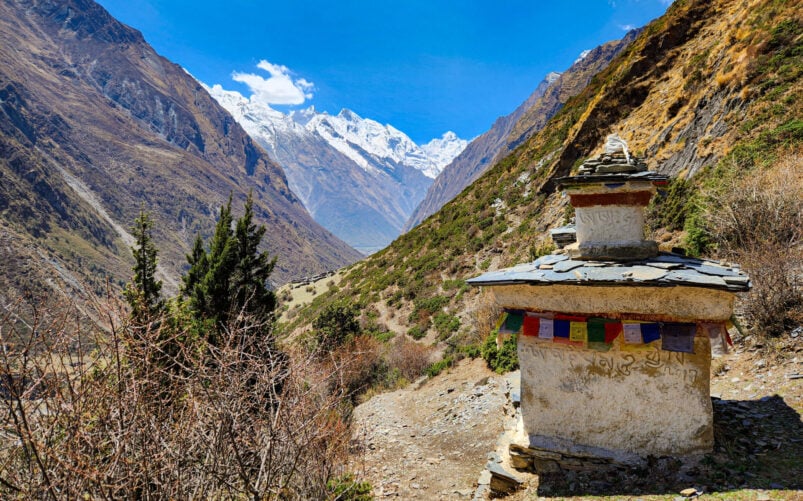 Stupa et drapeaux de prière le long d’un sentier de montagne dans la vallée de Tsum, Népal.