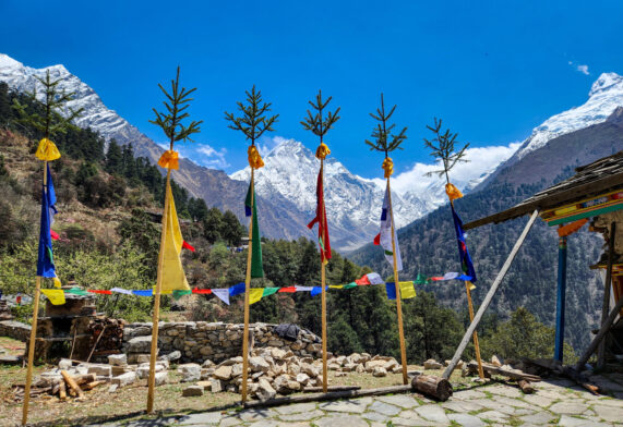 Drapeaux de prière et décorations traditionnelles devant les sommets enneigés de la vallée de Tsum, Népal.