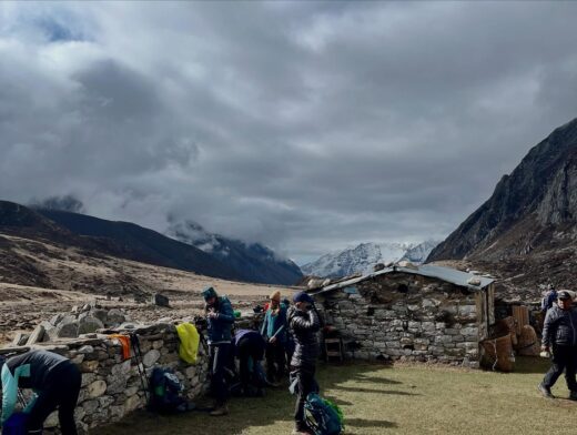 Randonnée avec les Chèvres de montagne au Népal. Groupe de randonneuses se préparant près d’un refuge de pierre dans une vallée himalayenne entourée de montagnes enneigées – trek et aventure avec Karavaniers