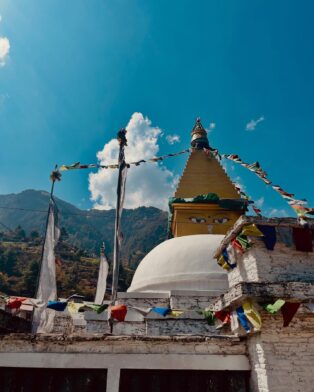 Stupa bouddhiste orné de drapeaux de prières colorés au cœur des montagnes himalayennes, une étape culturelle marquante d’un trek d’aventure avec Karavaniers.