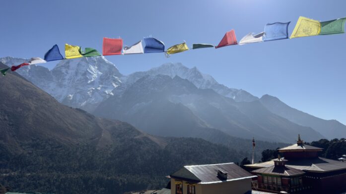 Drapeaux de prières colorés au-dessus du monastère de Tengboche avec les sommets himalayens en arrière-plan, scène emblématique de trek au Népal avec Karavaniers.