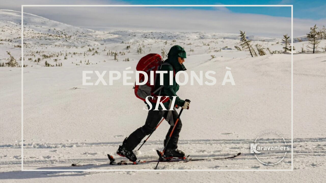 Une personne en tenue d'hiver avec un sac à dos rouge traverse à ski le paysage enneigé des Monts Groulx sous un ciel nuageux. Le texte EXPÉDITIONS À SKI et le logo des Karavaniers sont superposés à l'image. - Karavaniers