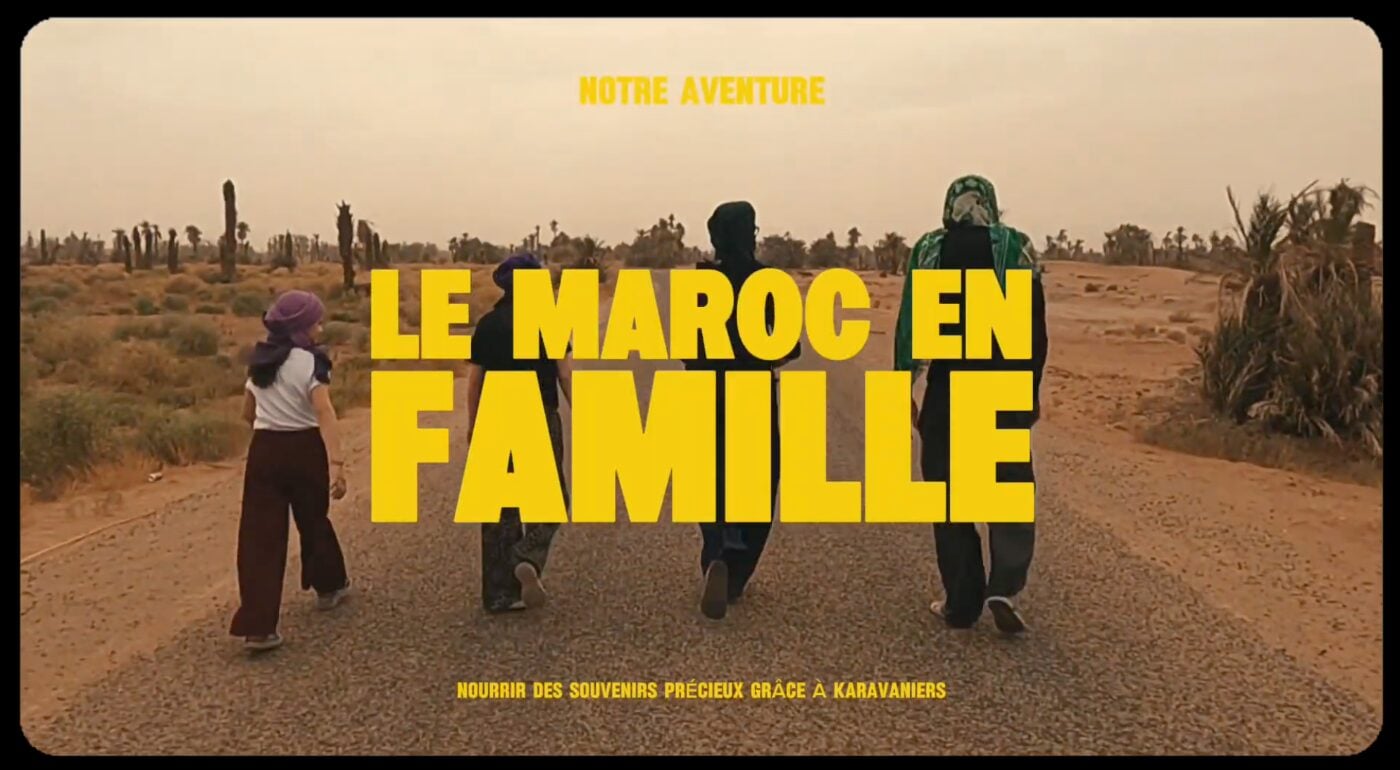 Quatre personnes s'éloignent sur une route de campagne avec des arbres en arrière-plan. Le texte en gros caractères jaunes en français indique "LE MAROC EN FAMILLE". Le texte en plus petit au-dessus indique, NOTRE AVENTURE, et en dessous, Voyage au Maroc en famille : Nourrir des souvenirs précieux grâce à Karavaniers. - Karavaniers