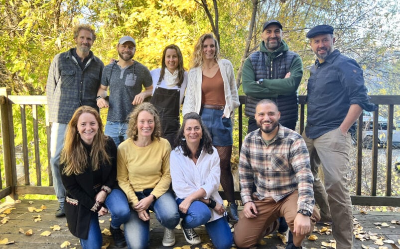 Un groupe de onze adultes a posé sur une terrasse en bois devant des arbres aux feuilles d'automne jaunes lors d'un voyage en République dominicaine. - Karavaniers